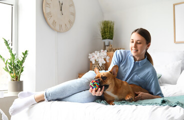 Young woman with cute French bulldog in bedroom