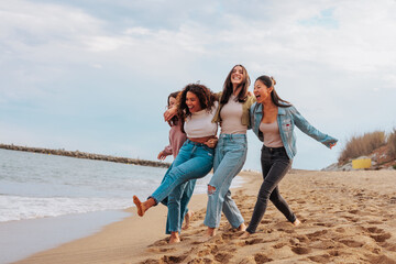 four young women jumping together on beach