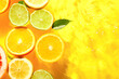 canvas print picture - Different citrus fruit slices and leaves in water on yellow background