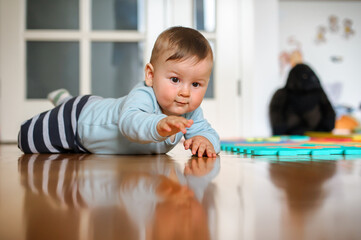 Wall Mural - Cute baby boy crawls on the home floor, explore the world and learn to move. Love and family emotion