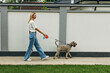 Side view of a blond woman taking the dog for a walk.