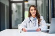 © bnenin - Portrait of a pretty female doctor working at the office with papers and a laptop.
