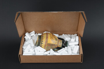 Wall Mural - Antique vessel packed in cardboard box on black background