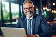 © Starmarpro - Smiling mid aged businessman ceo wearing suit sitting in office using laptop. Mature businessman professional executive. High quality photo Generative AI