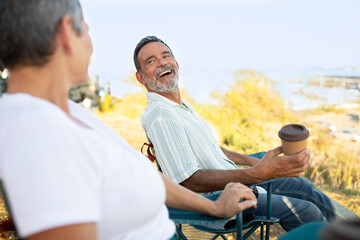 Joyful Mature Couple Sitting Drinking Coffee At Ocean Outdoor