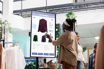 customer using touch display shopping for fashion items in clothing store, interactive board. africa