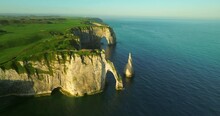 A Drone Flies Over The Coastline With Chalk Cliffs In Etretat, France. Aerial View Of A Picturesque Place On The Shores Of The Atlantic Ocean. Rocks, Cliffs, Hills Recorded From A Drone