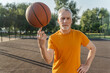 © Maria Vitkovska - Portrait of confident handsome senior man playing basketball, spinning ball on one finger looking at camera standing on the street. Sport, healthy lifestyle concept