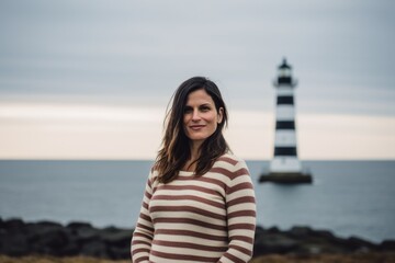 Wall Mural - Portrait of a beautiful young woman in front of a lighthouse.