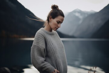 Wall Mural - Portrait of a beautiful girl in a sweater on the background of mountains and lake