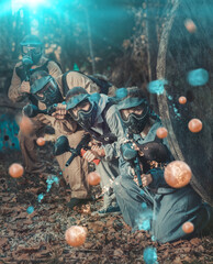 Wall Mural - Paintball players aiming and shooting with guns at opposing team outdoors, image with light effects