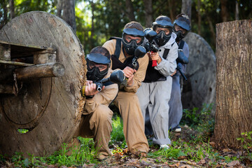 Wall Mural - Portrait of adult people with guns during paintball game on outdoors arena