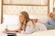 © Wavebreak Media - Smiling plus size caucasian young woman thinking and writing in book while lying on bed