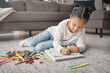 © L Ismail/peopleimages.com - Young girl, kid and pencils on floor with coloring book in living room for education, learning or creative development. Cute child, books and crayons for writing, drawing or creativity of art project