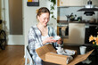 © Westend61 - Smiling young woman unpacking ceramic bowls from cardboard box at home