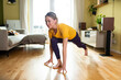 © Westend61 - Young woman exercising on wooden floor at home