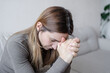 © Julija - Young depressed woman sitting on sofa in living room. She feeling sad and worried suffering depression in mental health.