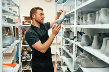 Shelves with shoes. Technician working indoors