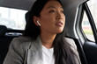 © gpointstudio - Business Chinese woman driving in a taxi and using earphones