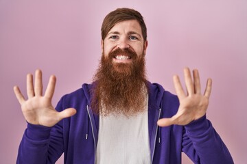 Sticker - Caucasian man with long beard standing over pink background showing and pointing up with fingers number ten while smiling confident and happy.