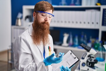 Sticker - Young redhead man scientist reading report holding sample at laboratory