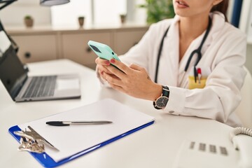 Poster - Young caucasian woman doctor using smartphone working at clinic