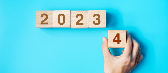 hand holding wooden cube block with 2024 text on blue background. Resolution, plan, review, goal, start and New Year holiday concepts