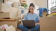 © Krakenimages.com - Young beautiful hispanic woman using laptop sitting on floor at new home