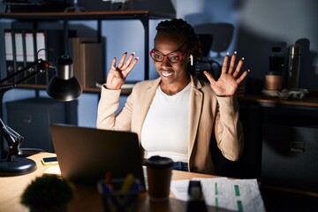 Sticker - Beautiful black woman working at the office at night showing and pointing up with fingers number nine while smiling confident and happy.