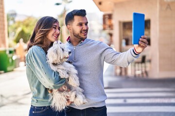 Wall Mural - Man and woman holding dog making selfie by the touchpad at street