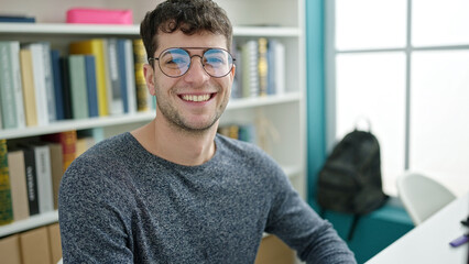 Sticker - Young hispanic man student looking at the camera at library university