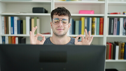 Wall Mural - Young hispanic man using computer doing meditation at library university