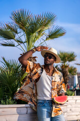 Wall Mural - Black ethnic man enjoy summer vacation on the beach, sombrero and a watermelon