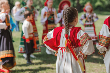 Wall Mural - Russian folk traditions. Folk festivals. Children in beautiful Russian traditional outfits sing songs, dance and lead a round dance in Tsaritsyno Park. National Russian clothes. 