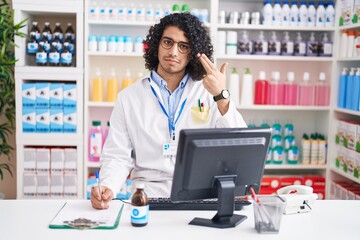 Wall Mural - Hispanic man with curly hair working at pharmacy drugstore shooting and killing oneself pointing hand and fingers to head like gun, suicide gesture.