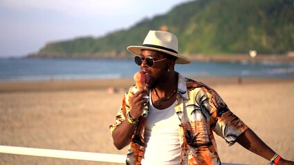 Wall Mural - Black ethnic man enjoy summer vacation on the beach eating an ice cream having fun