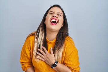 Canvas Print - Young hispanic woman standing over isolated background smiling and laughing hard out loud because funny crazy joke with hands on body.