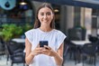 © Krakenimages.com - Young beautiful hispanic woman smiling confident using smartphone at coffee shop terrace