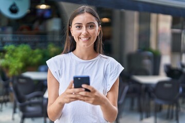 Wall Mural - Young beautiful hispanic woman smiling confident using smartphone at coffee shop terrace