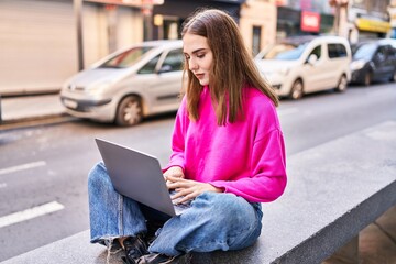 Poster - Young woman using laptop sitting on bench at street