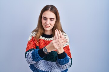 Sticker - Young hispanic girl standing over blue background suffering pain on hands and fingers, arthritis inflammation