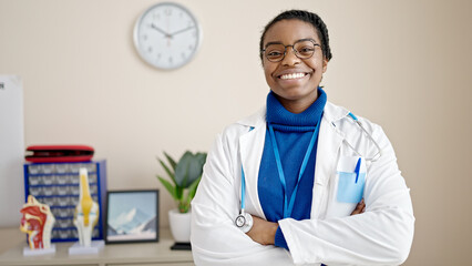 Wall Mural - African american woman doctor smiling confident standing with arms crossed gesture at clinic