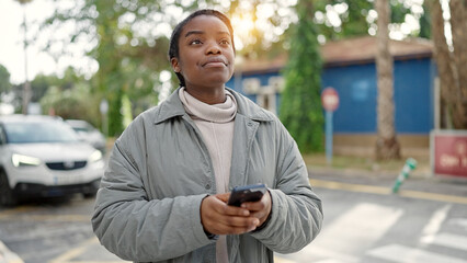 Poster - African american woman using smartphone with serious expression at street