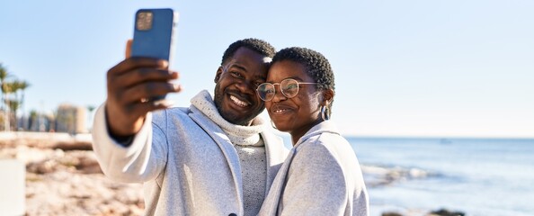 Wall Mural - Man and woman couple standing together make selfie by the smartphone at seaside