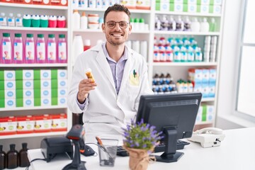 Wall Mural - Young hispanic man pharmacist smiling confident holding pills bottle at pharmacy