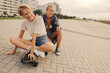 © Jacob Lund - Two girlfriends laugh happily as they play with a skateboard in the city