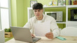 © Krakenimages.com - Young hispanic man using laptop reading document at dinning room