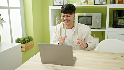 Sticker - Young hispanic man using laptop sitting on table dancing at dinning room