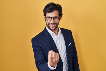 Poster - Handsome latin man standing over yellow background beckoning come here gesture with hand inviting welcoming happy and smiling