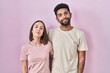 © Krakenimages.com - Young hispanic couple together over pink background relaxed with serious expression on face. simple and natural looking at the camera.